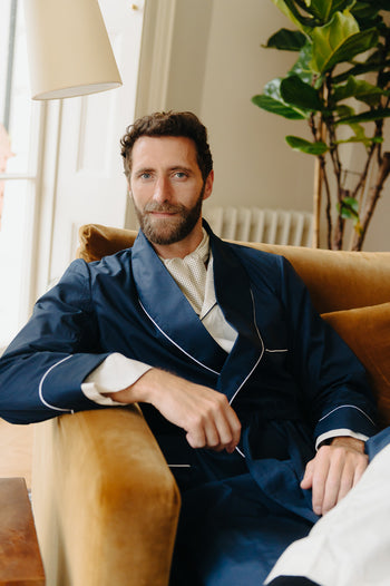 Men's nightwear, man sat in armchair wearing navy blue dressing gown for Autumn