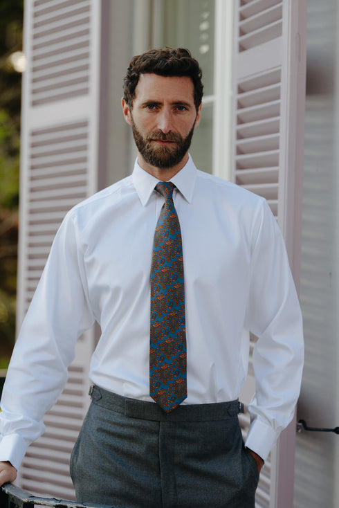 Male model wearing plain white business shirt with motif silk tie stood outside on balcony