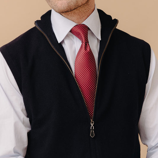 Close up of model stood wearing Welbeck Geelong Wool Zip Up Gilet in Navy over white shirt and red spot  tie against a cream plain background
