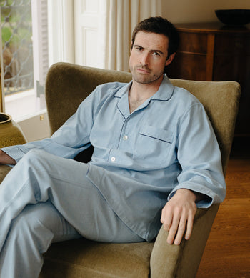 Male model sat in armchair wearing Budd pyjamas for Autumn nightwear