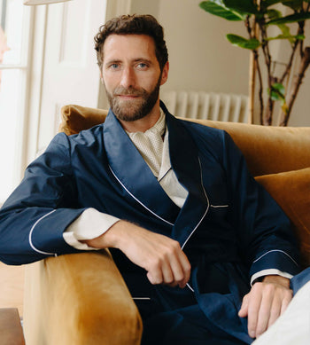 Men's nightwear, man sat in armchair wearing navy blue dressing gown for Autumn